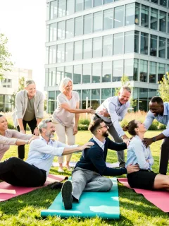 Empleados felices participando en un programa de bienestar corporativo, sonriendo y colaborando en una actividad al aire libre.