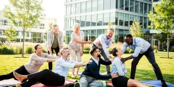 Empleados felices participando en un programa de bienestar corporativo, sonriendo y colaborando en una actividad al aire libre.
